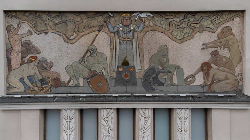 Attēlā redzama mākslinieka Jaņa Rozentāla veidotā freska uz Rīgas Latviešu biedrības nama fasādes. Kompozīcijas centrā pie liela, sazarota koka stāv stalta vīrieša - valdnieka figūra, kas vienā rokā tur paceltu āmuru, uz otras nosēdies gulbis. Priekšā dekoratīvā traukā uguns. Ap centrālo tēlu izvietotas vairākas personu kailfigūras. Darbs veidots jūgendstila nacionālā romantisma manierē ar siltiem zemes toņiem — okeru, sarkanbrūnu un pelēkzilo.